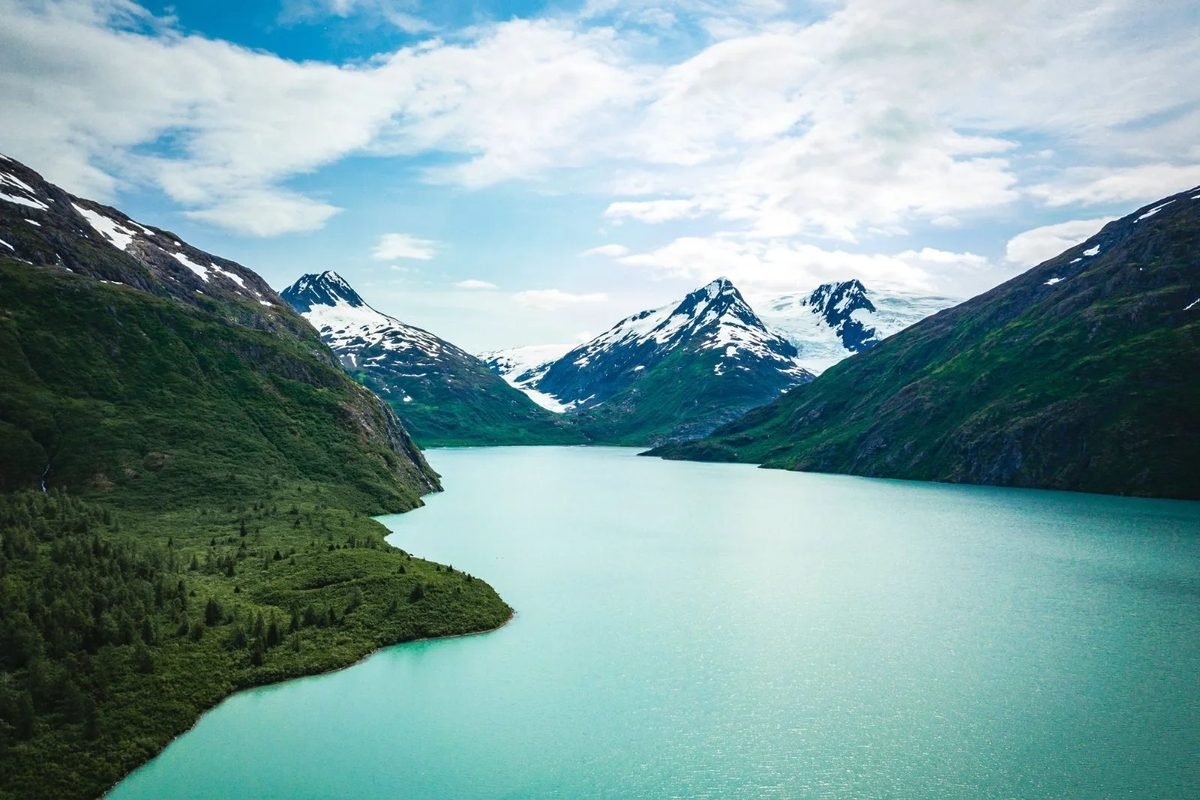 Un lago turquesa entre montañas nevadas en Alaska