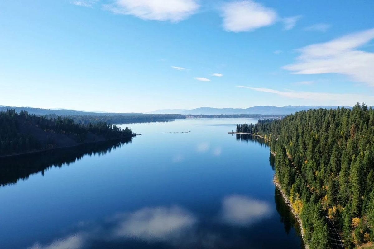 Un lago largo y tranquilo que refleja el cielo y el bosque de pinos cerca de McCall, Idaho