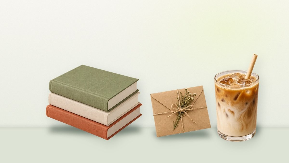 Stacked linen books, a kraft envelope and an iced latte on a sage table in morning light